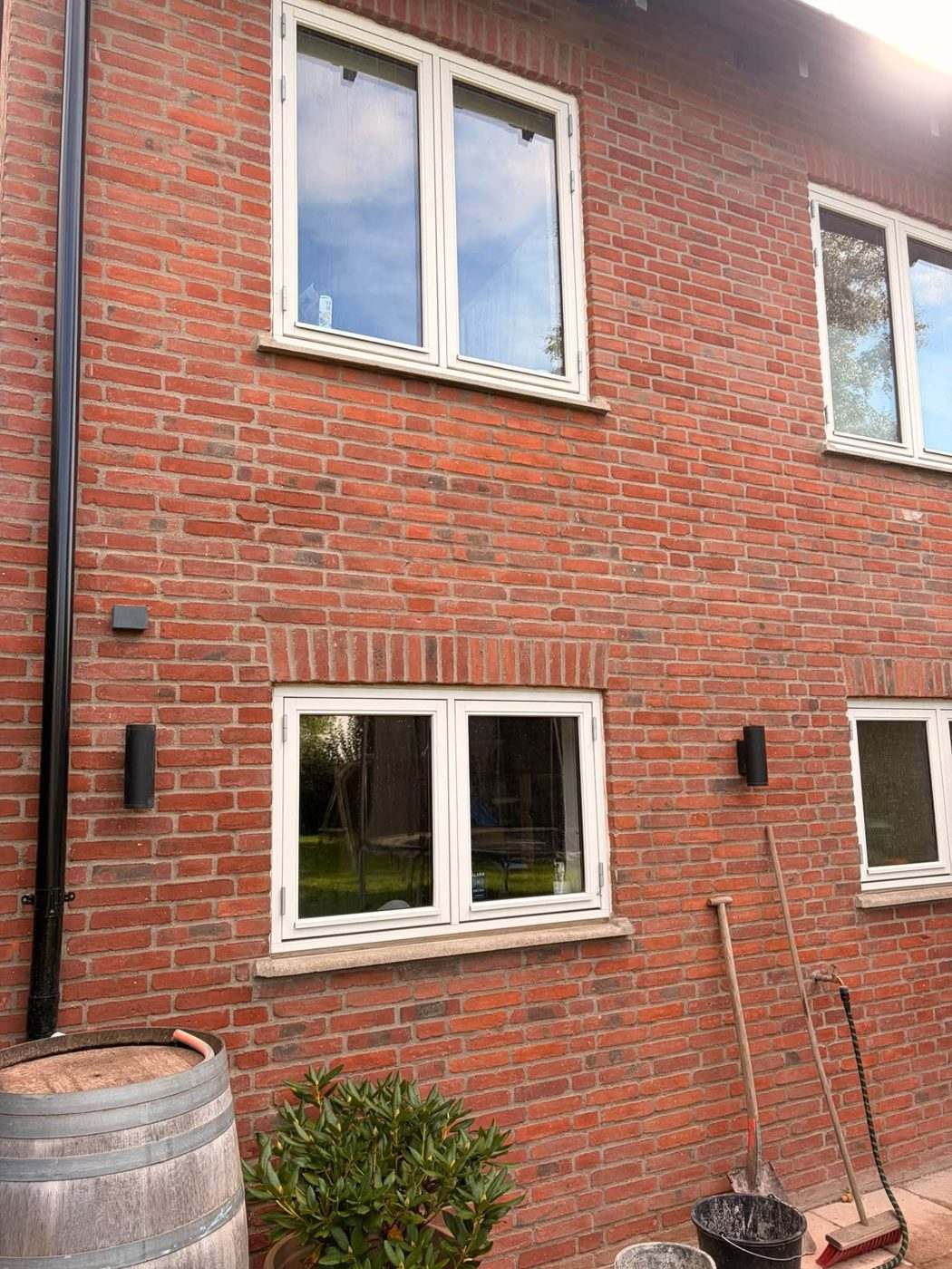 Murstensfacade i rød tegl med hvide vinduer og stik over vinduerne